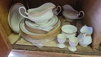 Wide view of the entire Royal Albert Burlington china set stacked and arranged with gravy boat, cream and sugar set, egg cups, and plates.