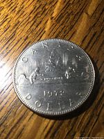 Reverse side of the 1972 Canadian silver dollar coin featuring a canoe with two paddlers and Canadian inscriptions.