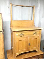 Front view of solid wood antique washstand with towel rack, showing drawer and cabinet doors.