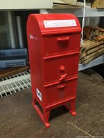 Front angle view showing front door with handle, coin slot, and spigot detail on red metal bank.