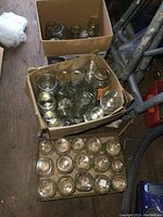 Top view of three cardboard boxes filled with clear glass canning jars in various sizes and shapes.