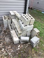 Concrete blocks stacked outside on dirt and gravel ground near siding of building