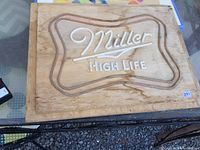 Full view of the wooden Miller High Life sign showing its carved and raised lettering and natural wood grain.
