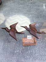 Pair of hand carved rosewood birds and small wood tray displayed on a glass surface.