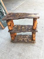 Front perspective view of the solid wood live edge three-tier shelf showing the rustic texture and the cylindrical leg supports.
