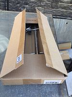 Shepherd's hook partially visible inside closed cardboard box from top view