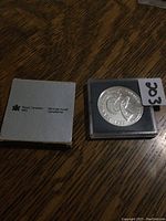 The silver dollar coin displayed alongside the Royal Canadian Mint cardboard box sleeve.