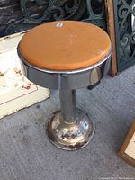Side view showing chrome base with rust and orange vinyl cushioned round seat