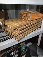 Stack of 10 solid wood shelves with visible slat design, roughly 31x10 inches each, with a bag containing multiple 12-inch wooden legs placed on shelving unit.