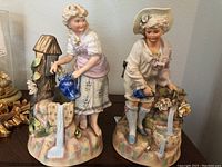 Pair of antique bisque ware figurines depicting young ladies pouring water from rustic stand pipes, showing size and overall detail.