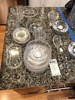 Photo showing the majority of the thirty cut glass pieces arranged on kitchen counter surface.