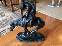 Right-side profile of entire bronze sculpture on hardwood floor showing figure and marble base