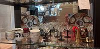 Wide shelf view showing Imari plates, bowls, cups, crystal glasses and bells
