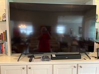 Front view of Samsung TV on stand with Bose soundbar and remote on cabinet
