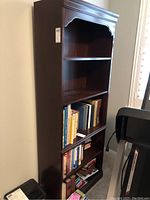 Front and angled view showing the full five-shelf bookcase with books on lower shelves.