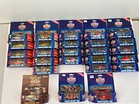 Top view of multiple Racing Action Platinum Series 1/64 die cast model cars and one truck in original blue display boxes with red and white accents, arranged in rows showing Limited Edition 1995 branding.
