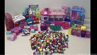 Full view of the large Shopkins collection with playsets and numerous collectible characters piled in front.