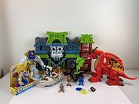Front view of the toy castle, dragons, pirate ship, boxed figure, and small character figures arranged together.
