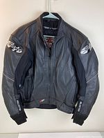Front view of black leather Joe Rocket motorcycle jacket with branded patches on shoulders and sleeve cuffs.