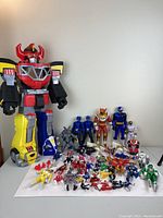 Full lot showing large Megazord figure, multiple smaller Power Rangers figures and vehicles arranged on a white surface.