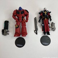 Two Warhammer 40K figures with accessories and display stands shown together.