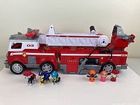 Full fire rescue truck with seven Paw Patrol character figures arranged in front and on the truck