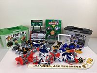 Wide view of football and hockey figurines, collectible storage boxes, video games, and sports memorabilia