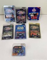 Seven limited edition die cast racing cars in original blister packaging from Action Racing Collectables, various race car designs including Star Wars theme and a signed Joe Ruttman car box.