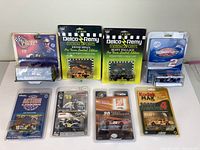Nine vintage die cast collectible racing cars in original packaging arranged in rows on a white surface.
