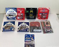 Seven vintage 1:64 scale die cast NASCAR collectible cars in original blister card packages on a white surface.