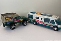 Image showing both the Nylint metal truck and the Outbounder camper vehicle side by side on a white background for full view of each item.