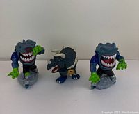 Three vintage Street Sharks action figures, two shark figures on gray bases and one triceratops figure, arranged side by side on a plain white background.
