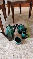 Full set of Blue Mountain Pottery coffee pot, tea pot, creamer, and sugar bowl shown on carpet with measuring tape nearby for scale.