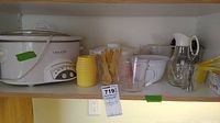 Wide shelf view showing all items including Crockpot, yellow measuring cups, clear liquid measuring cups, syrup bottle, white bowl, and utensils.