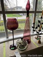 Three colored glass decor pieces placed on a window sill with visible outdoor scenery.