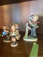 All four figurines on wood shelf showing size and grouping
