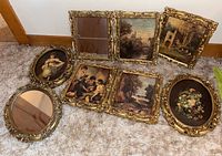 Overview of all six framed prints and two framed oval mirrors arranged on carpet floor, showing the detailed frames and pictures