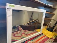 Framed rectangular mirror showing white frame and reflective surface placed on a colorful fabric background.