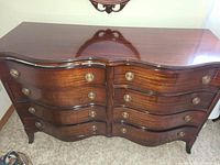 Front angled view of the Pepplers wooden dresser showing the eight curved drawers and brass pulls.
