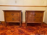 Front view of two matched Pepplers wood end tables with two drawers each and circular metal pulls, placed side by side on patterned carpet.