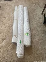 Three rolls of protective table covers with quilted patterns on two rolls and a smooth finish on one.