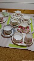 Multiple Royal Albert teacups and saucers displayed together with creamer and plate, showing patterns and condition.