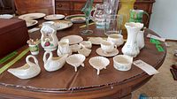 Wide view of multiple Belleek porcelain pieces on brown fabric surface.