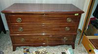 Full front view of the cedar chest showing wooden surface, three drawers with brass ring handles and slight scratches on wood.