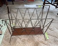 Front and side view of vintage metal and veneer magazine rack on carpet, showing wire frame design and wooden base