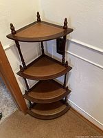 Full view of the four tier wooden corner shelf showing the shelves, spindles, and finials at the top