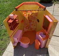 Photo of the folding American Girl Julie's Groovy Bathroom set showing the shower, toilet, sink, shelving unit, and mirror cabinet in bright orange, pink, and yellow with floral patterns.