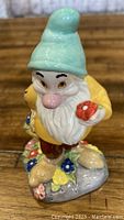 Front view of the Bashful figurine showing detailed face, turquoise hat, and floral base.