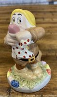Front view of Sneezy figurine showing facial expression, handkerchief, and colorful base