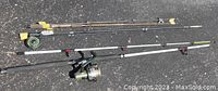 Three fishing rods laid on asphalt showing overall condition and details of rods and reels.